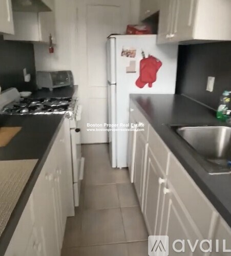 A kitchen with a white refrigerator and a red oven mitt magnet.