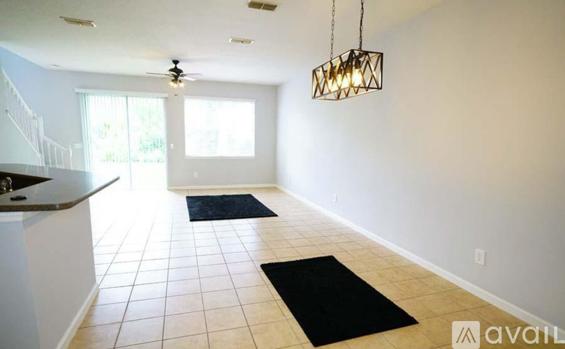 A spacious room with a kitchen area and a ceiling fan.
