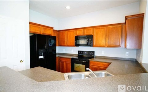 A kitchen with wooden cabinets and a black refrigerator.