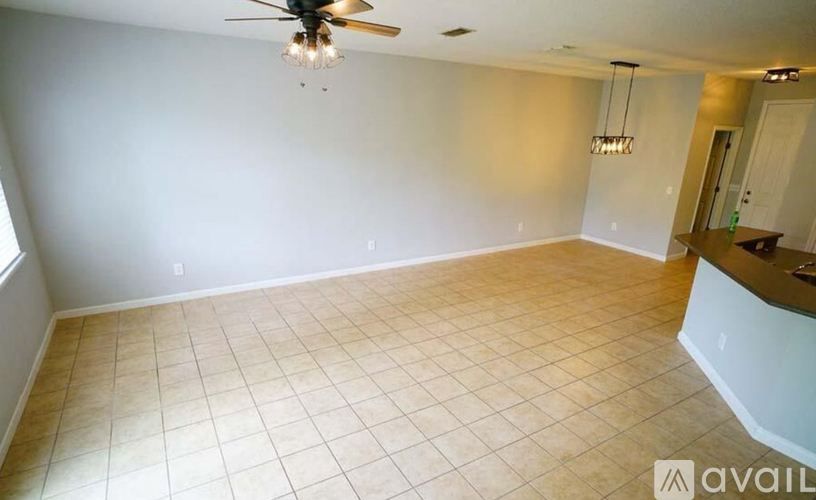 A spacious room with a ceiling fan and a bar area.
