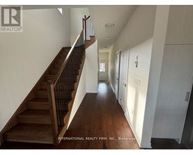 A hallway with a staircase and doors on the right side.