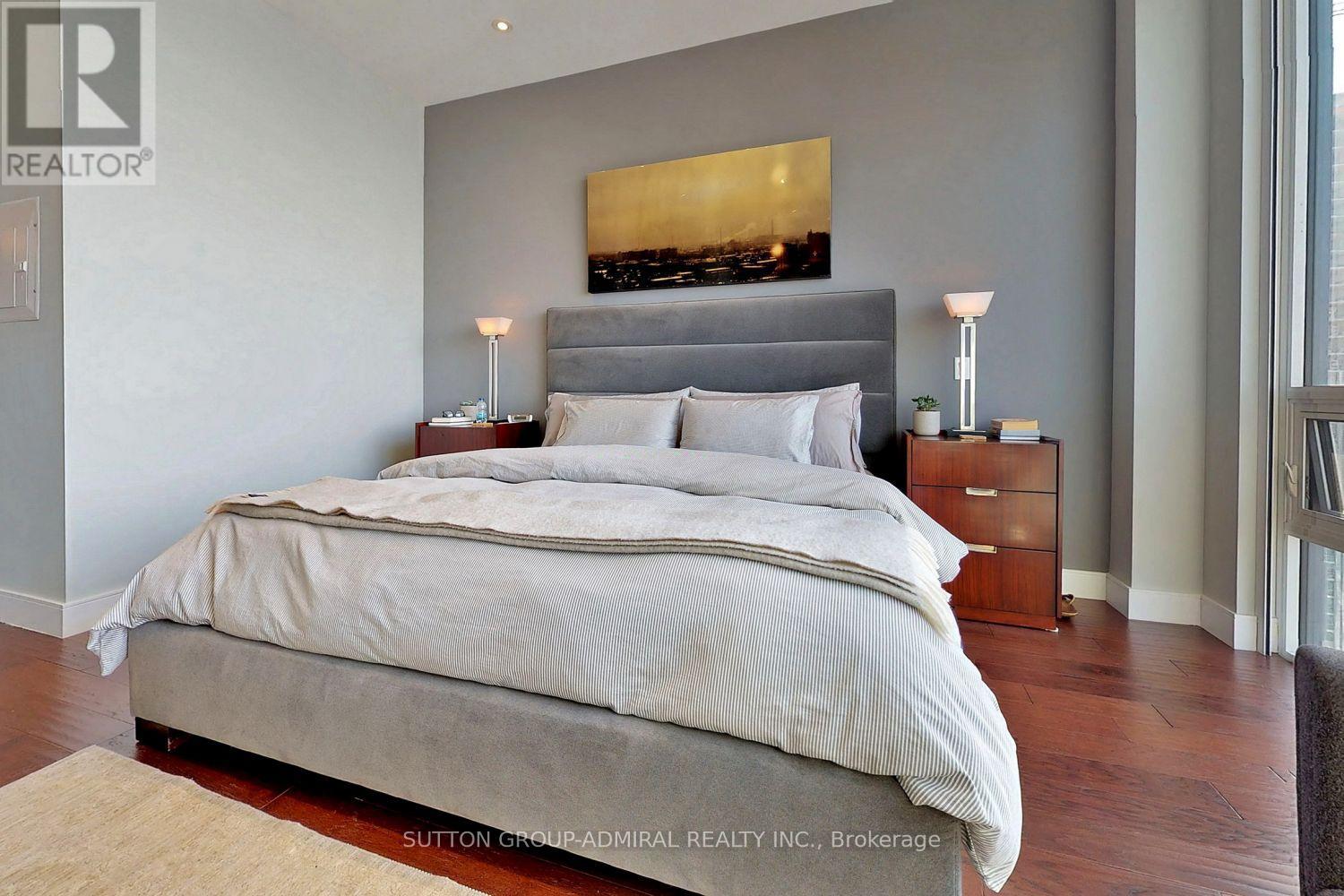 A bedroom with a large bed and a painting above it.
