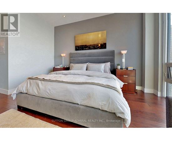 A bedroom with a large bed and a painting above it.