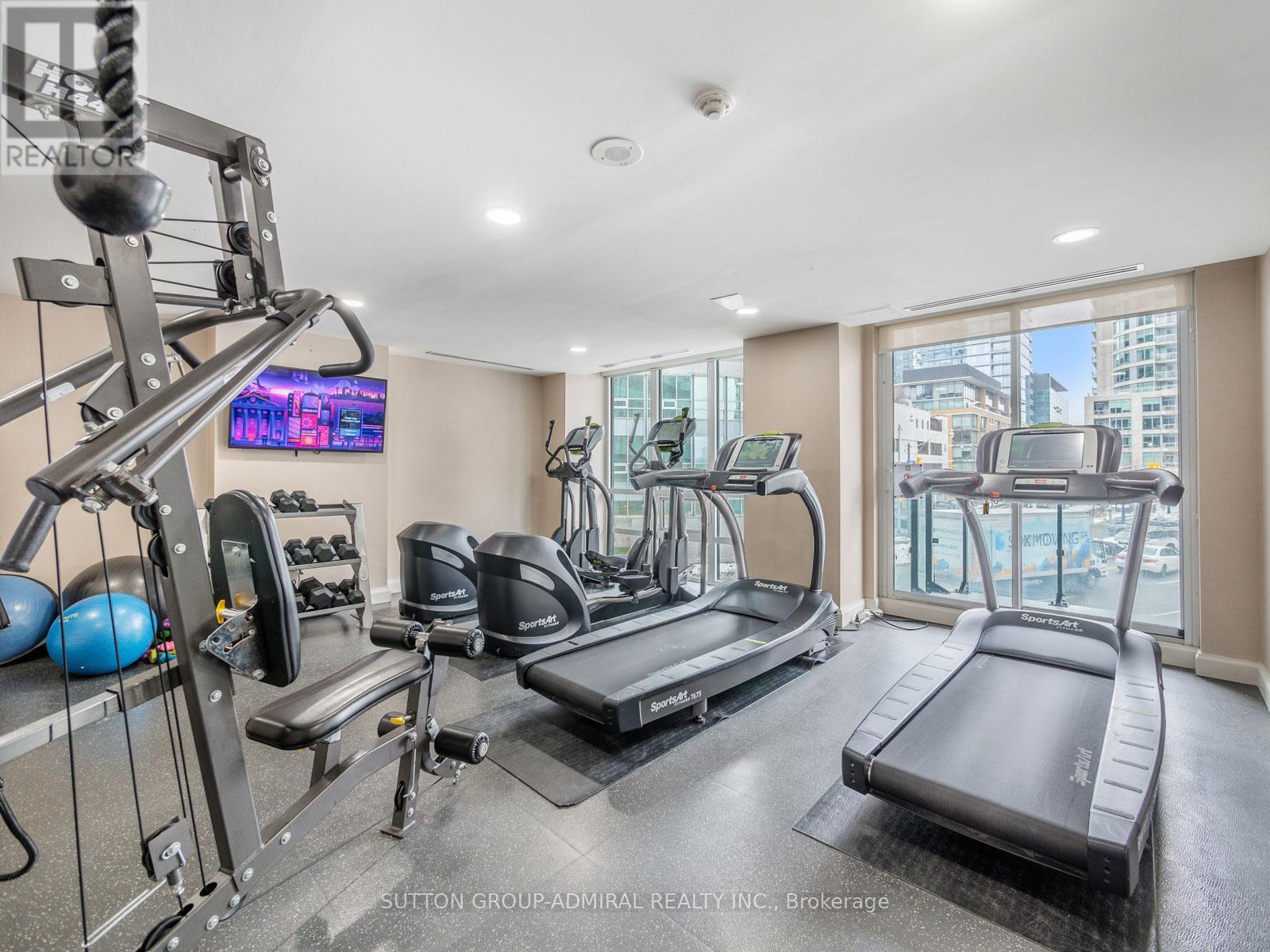 A well-equipped home gym with a television and a view of the city.