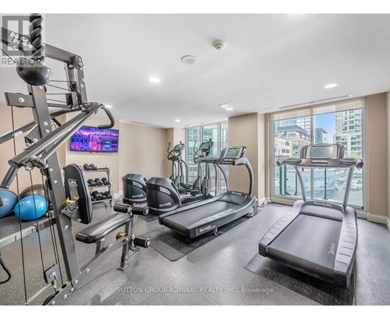 A well-equipped home gym with a television and a view of the city.