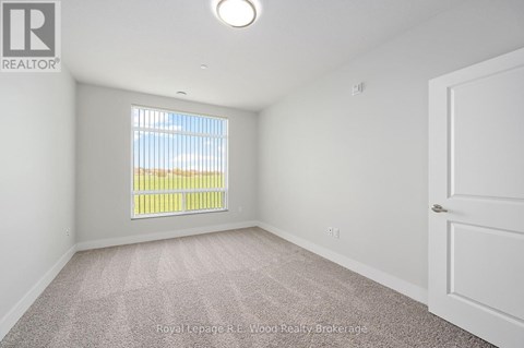 A white bedroom with a window and carpeted floor.