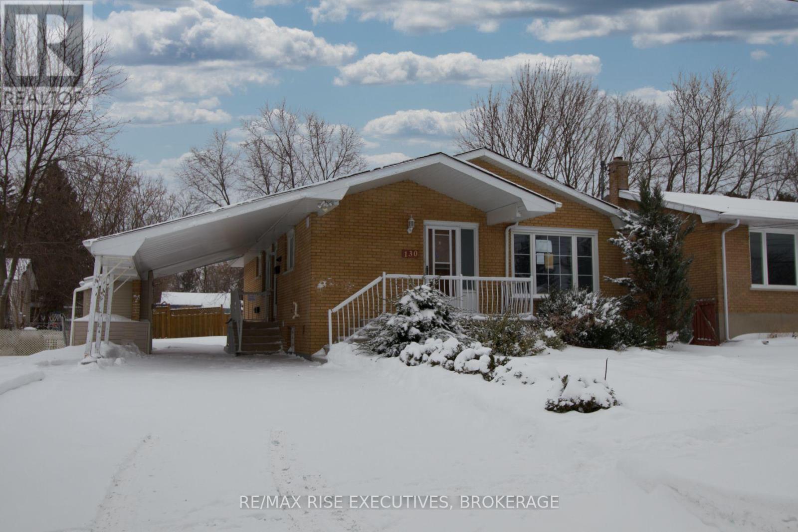 A house with snow on the ground and trees in the background.