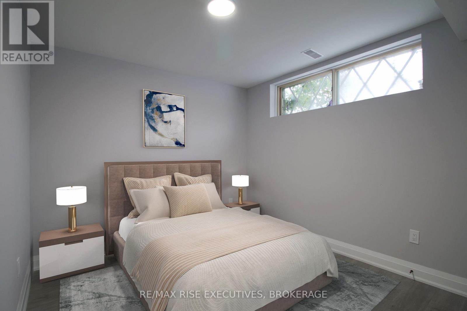 A bedroom with a large bed, two lamps, and a painting on the wall.