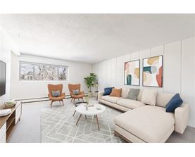 A living room with a white couch, two chairs, and a coffee table.