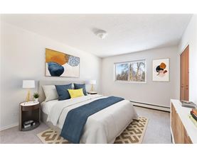 A bedroom with a bed, nightstand, and two framed pictures on the wall.