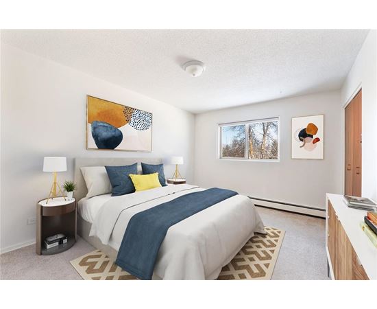 A bedroom with a bed, nightstand, and two framed pictures on the wall.