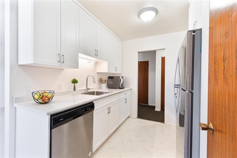 A kitchen with white cabinets and a black dishwasher.