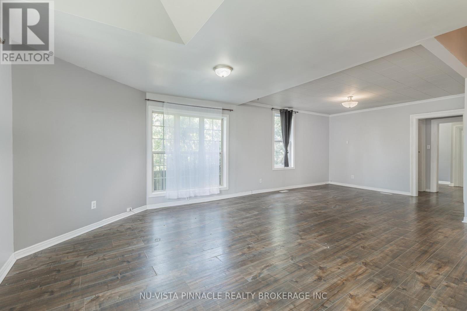 A room with wooden flooring and a window with curtains.
