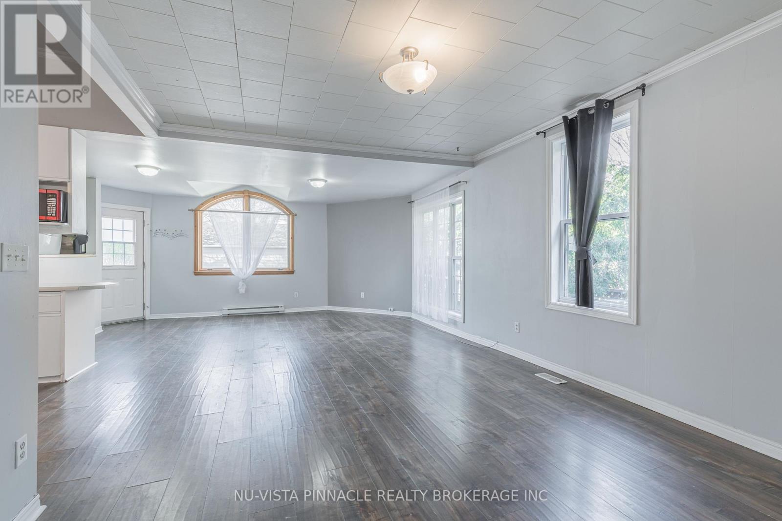A spacious room with wood flooring and white walls.