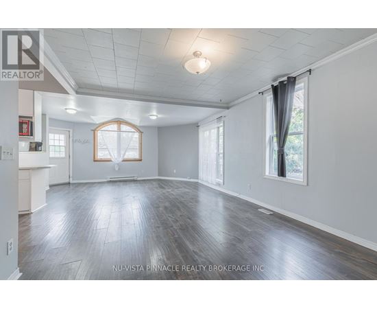 A spacious room with wood flooring and white walls.