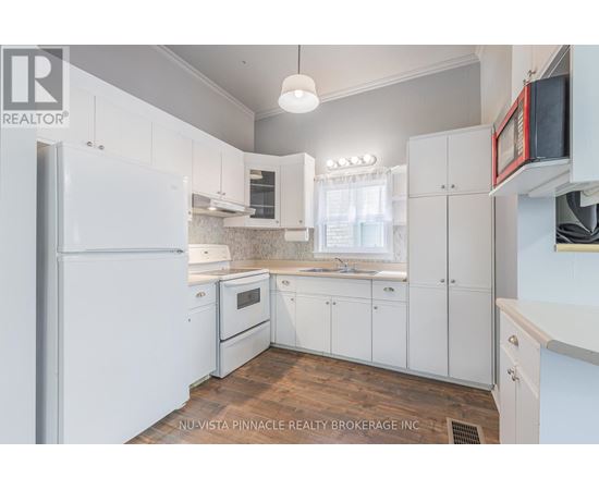 A kitchen with white cabinets and a refrigerator.