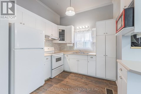 A kitchen with white cabinets and a refrigerator.