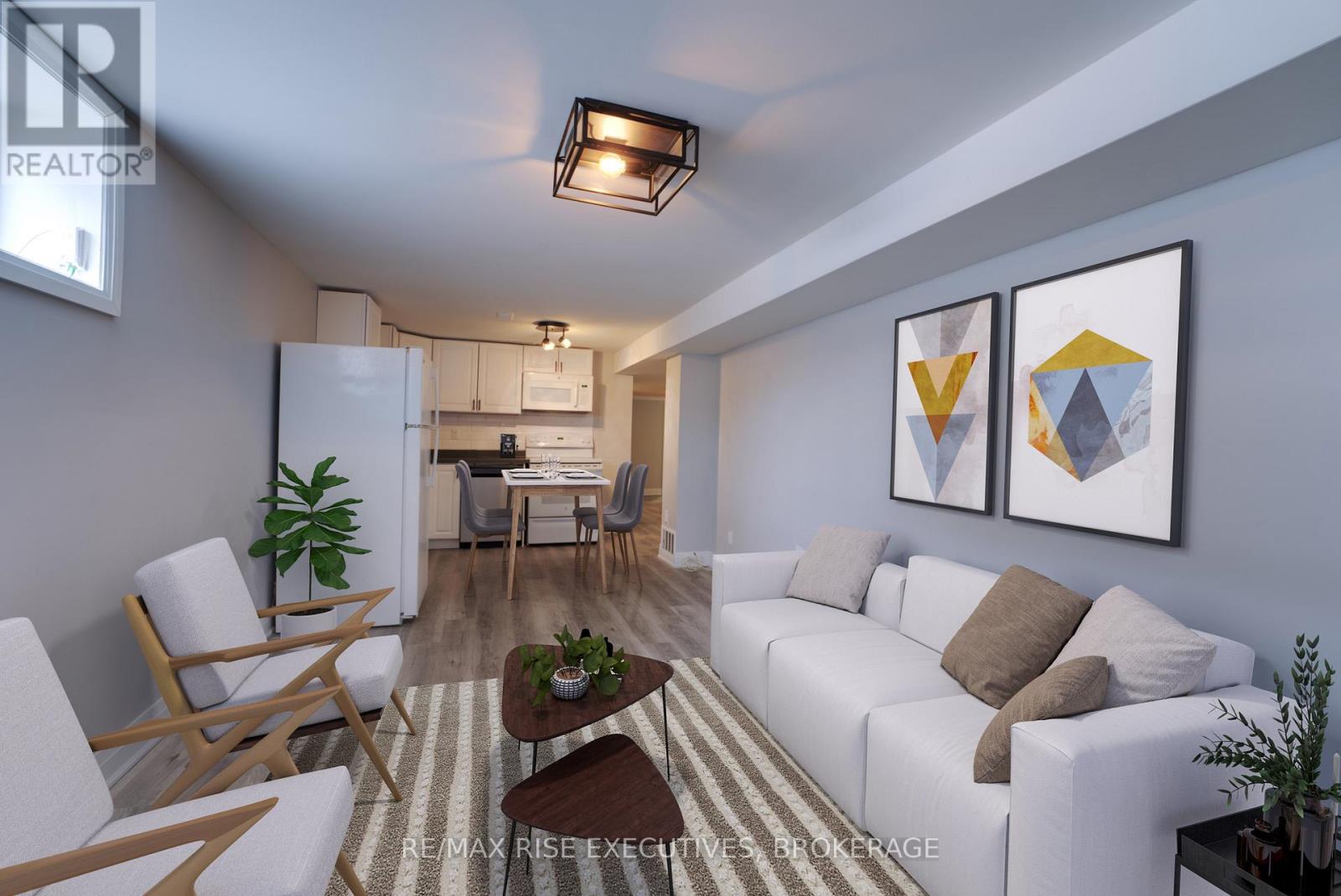 A living room with a white couch, a wooden chair, and a rug.