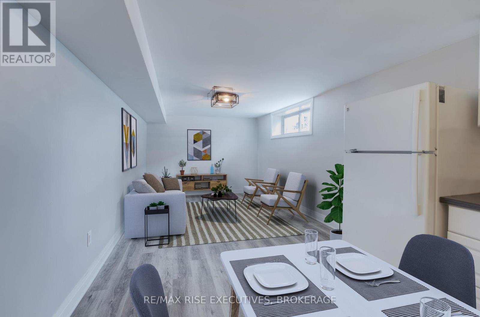 A dining room with a table set for two and a couch with a plant on it.