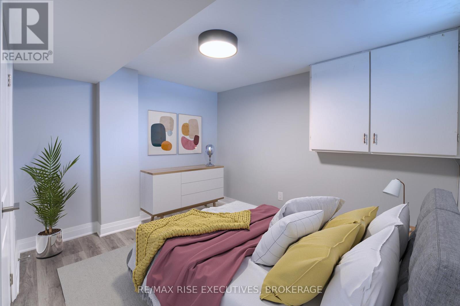A bedroom with a bed, pillows, and a plant.