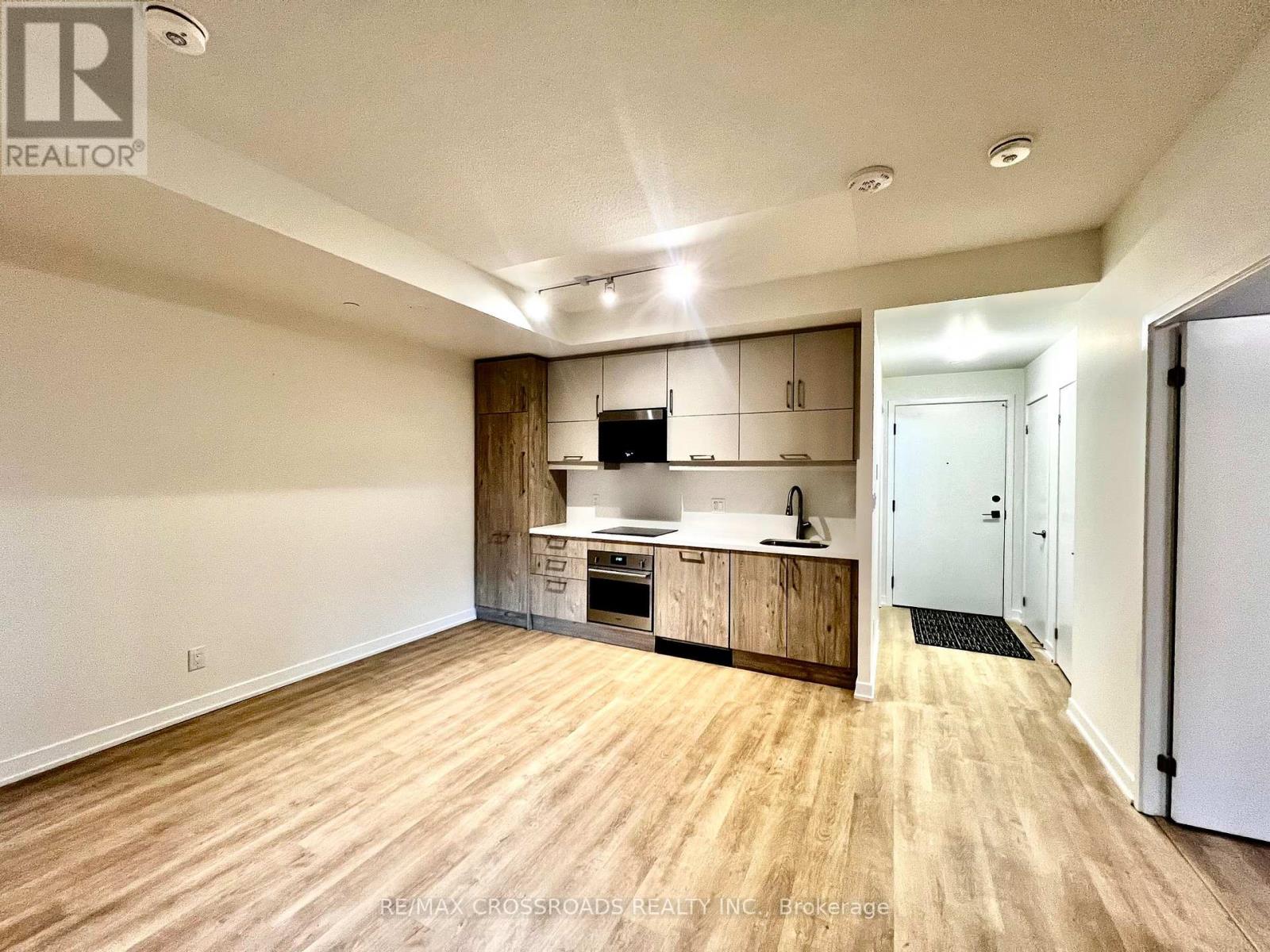 A spacious kitchen with wooden floors and white walls.