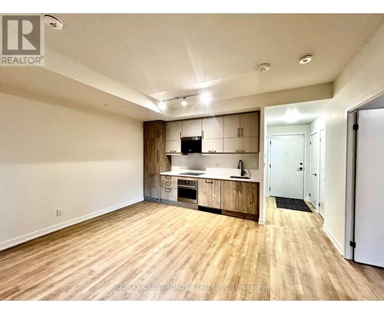 A spacious kitchen with wooden floors and white walls.