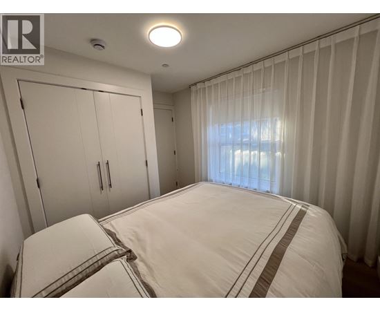 A bedroom with a large bed and a window with curtains.