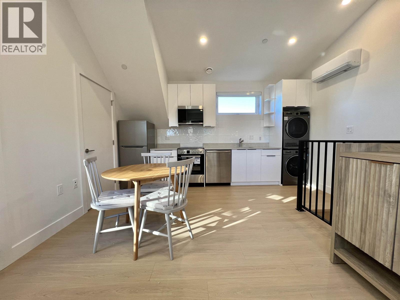 A kitchen with a table and chairs in the foreground and a refrigerator in the background.