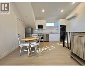 A kitchen with a table and chairs in the foreground and a refrigerator in the background.