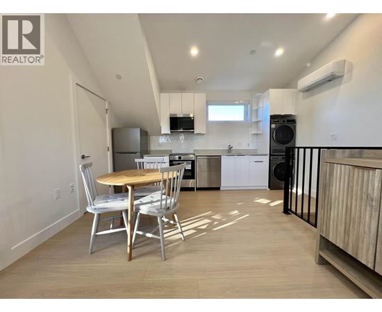 A kitchen with a table and chairs in the foreground and a refrigerator in the background.