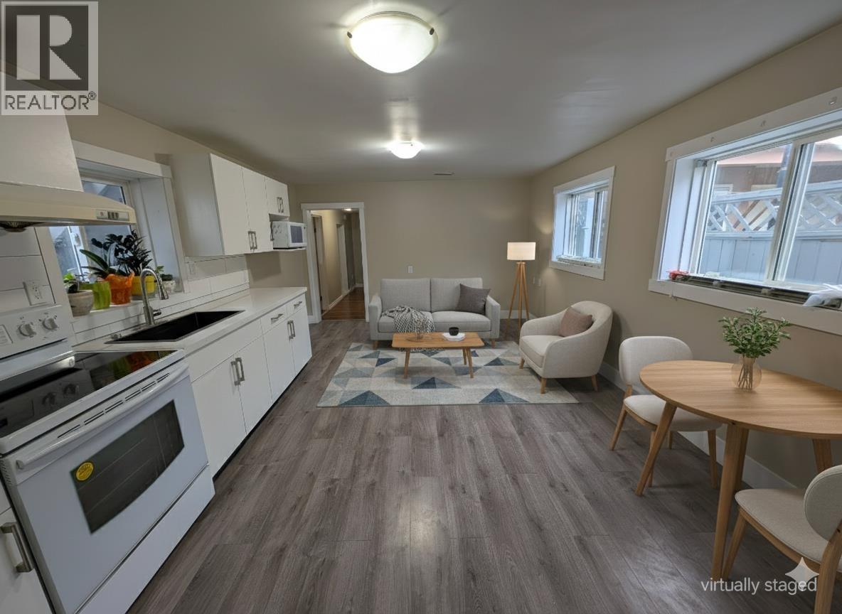 A virtual staging of a kitchen and living room with a dining table and chairs.