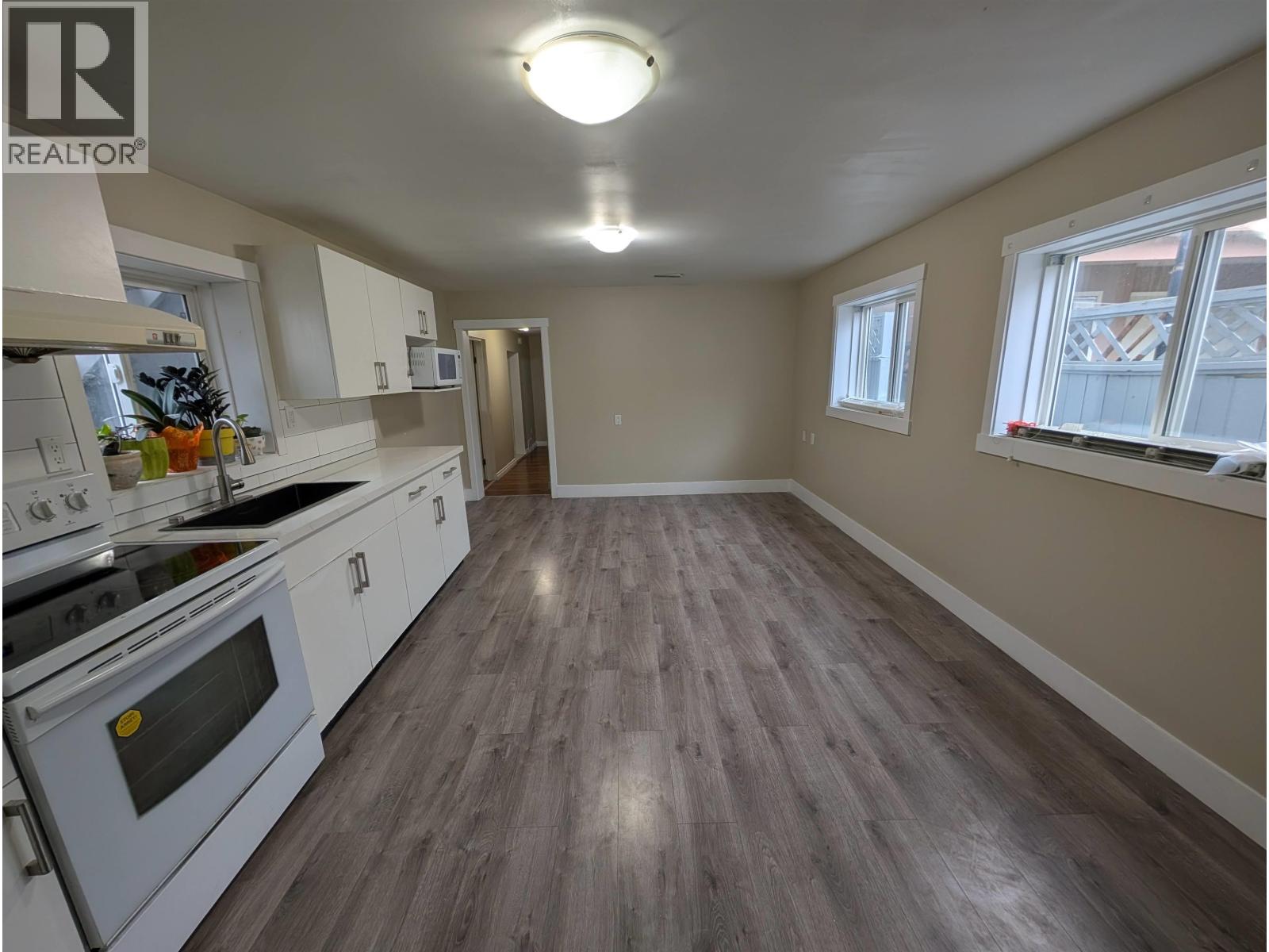A kitchen with white appliances and wood flooring.