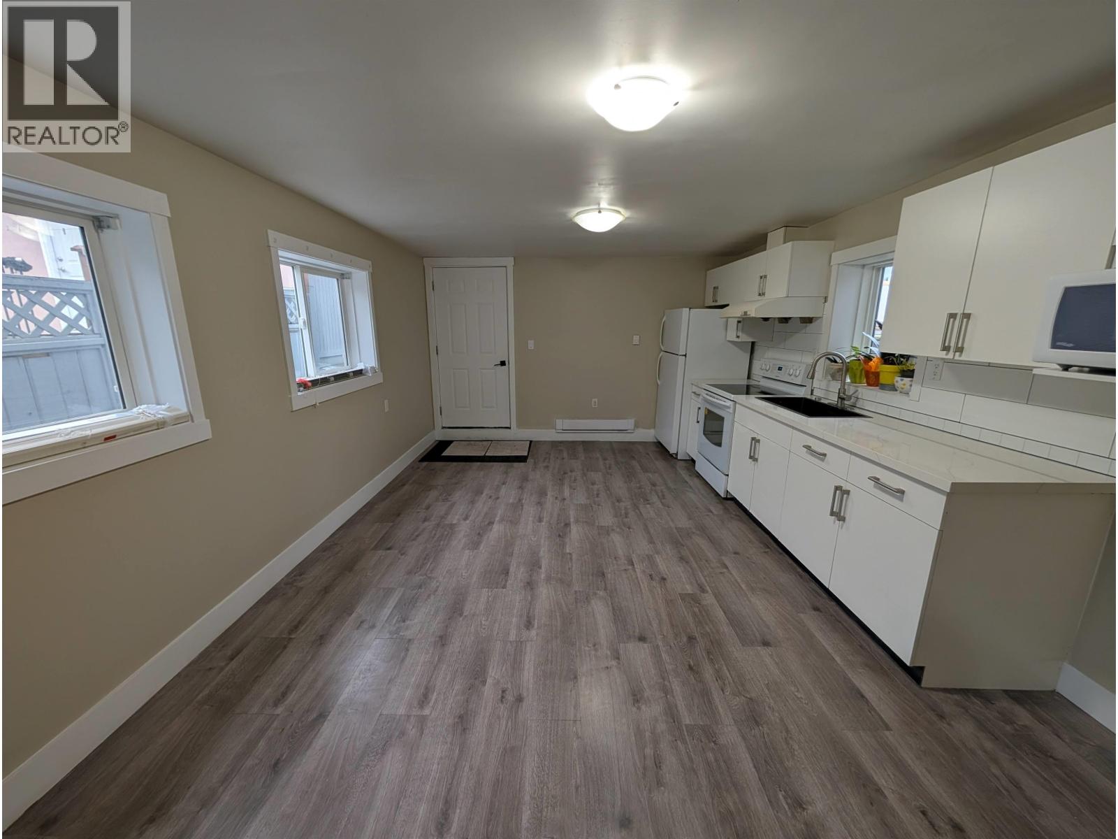 A kitchen with white cabinets and a wooden floor.