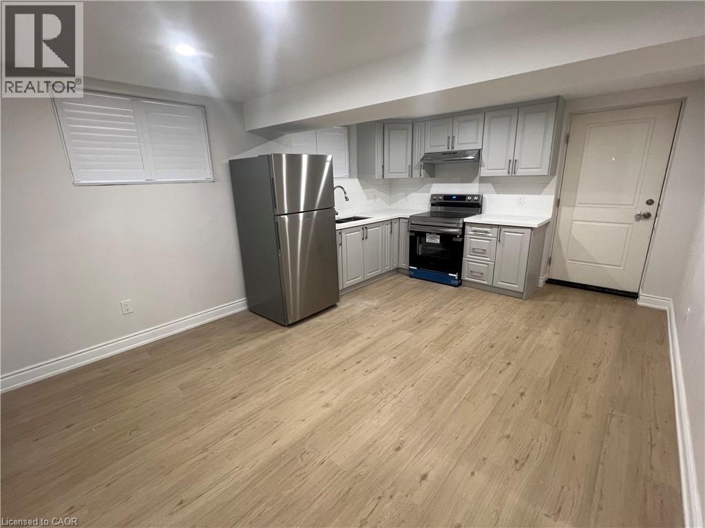 A kitchen with a refrigerator, oven, and cabinets.