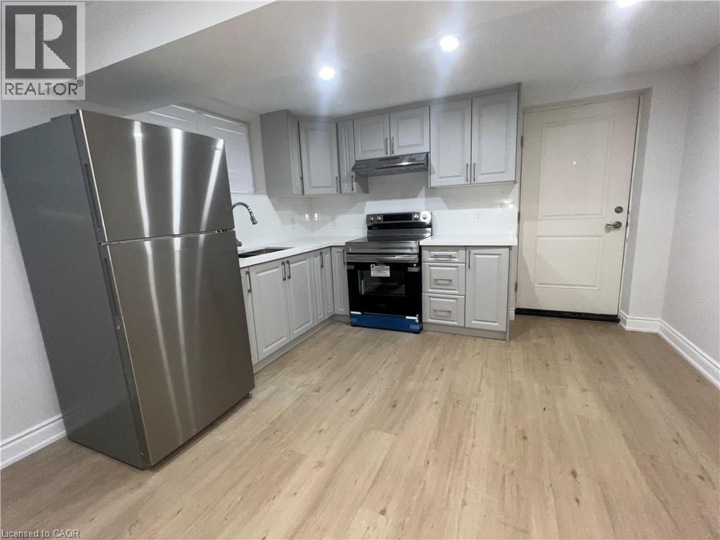 A kitchen with a refrigerator, oven, and cabinets.