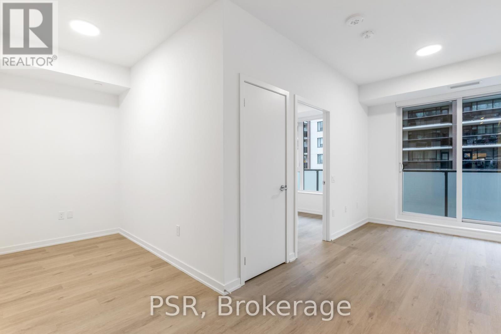 A room with a door and a window with a view of a building.