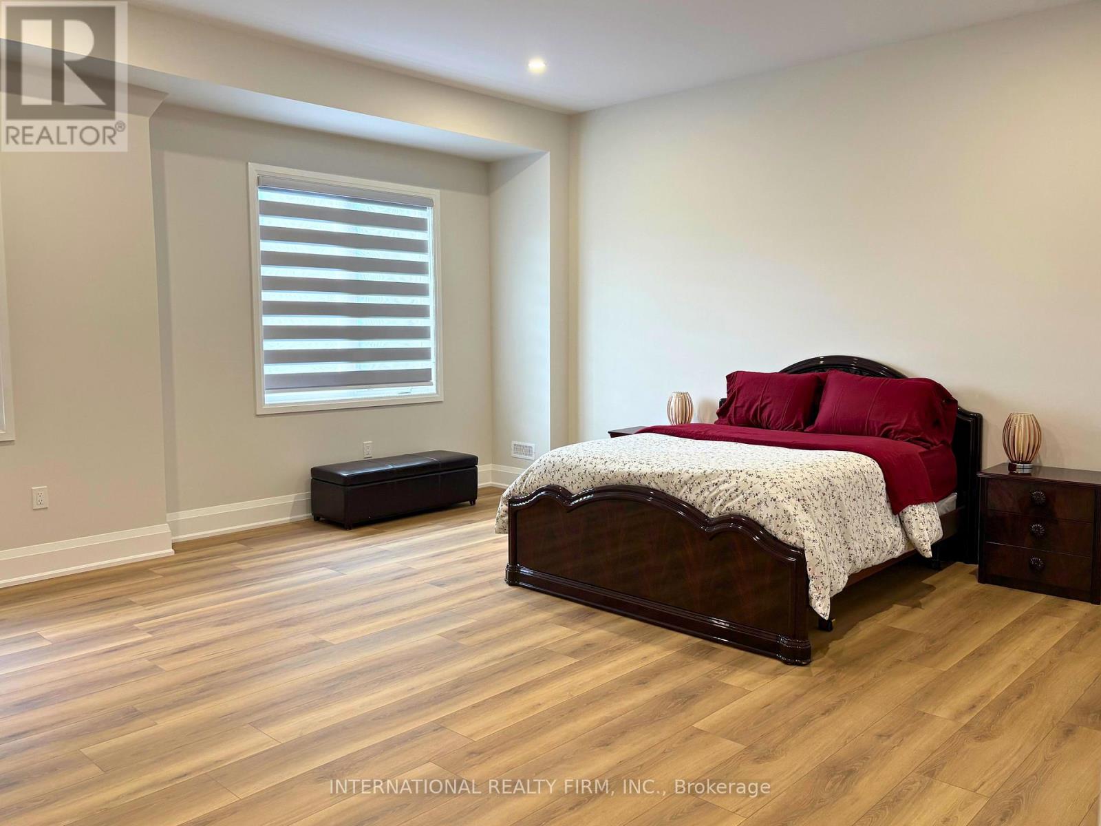 A bedroom with a bed, nightstand, and window with blinds.