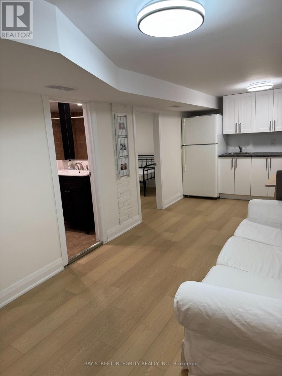 A white couch is in the foreground of a well-lit kitchen and living room.