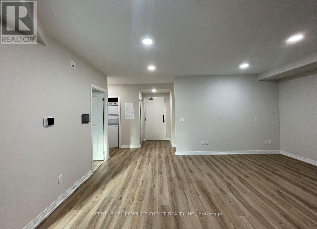 A spacious room with wooden flooring and white walls.