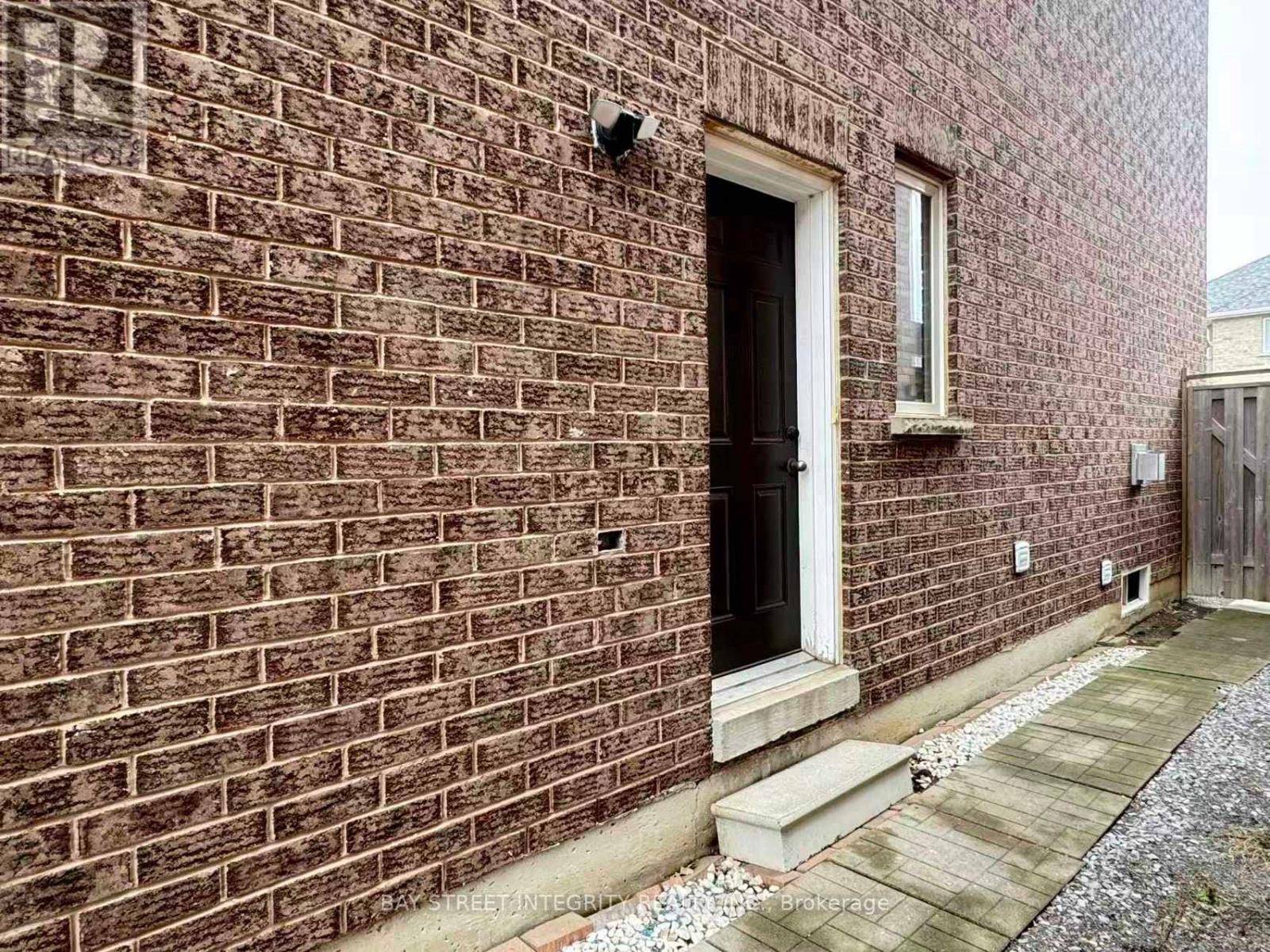 A brick building with a black door and a small window above it.