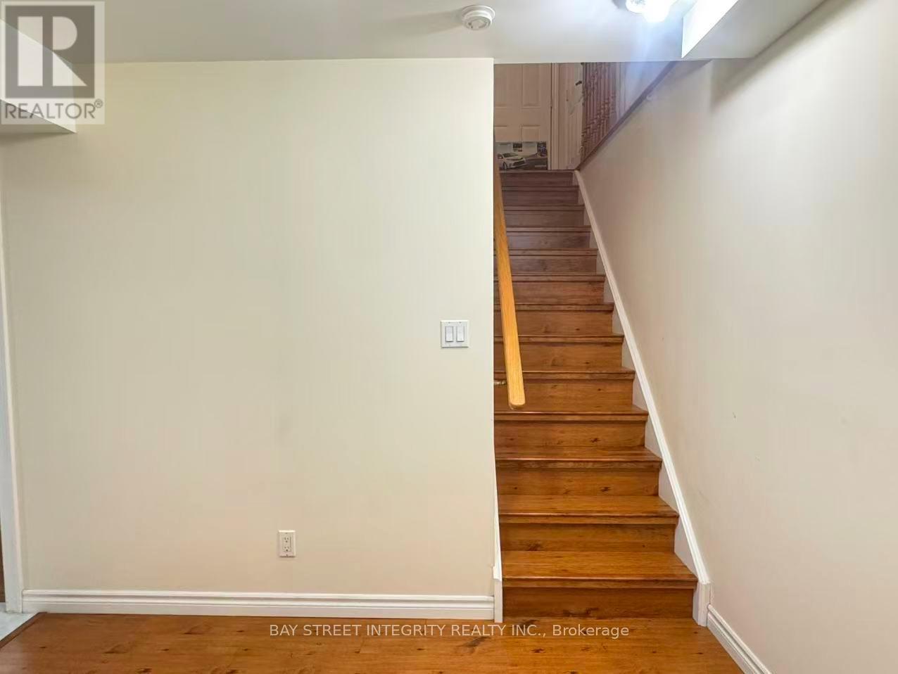 A staircase with a wooden handrail and white walls.