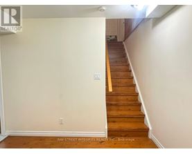 A staircase with a wooden handrail and white walls.