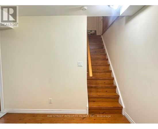 A staircase with a wooden handrail and white walls.
