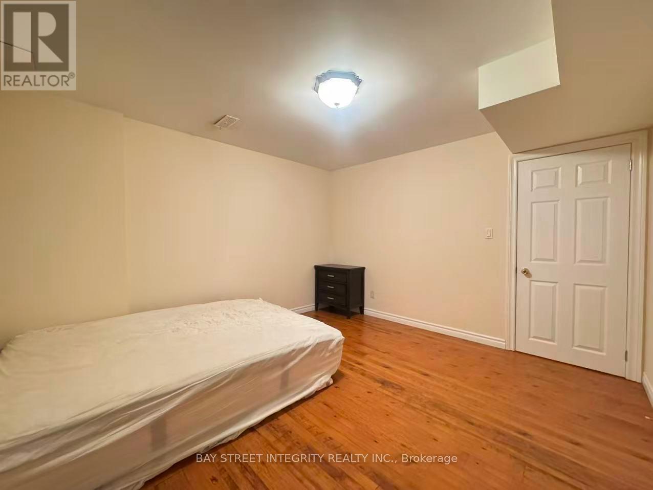 A bedroom with a bed, dresser, and a door.