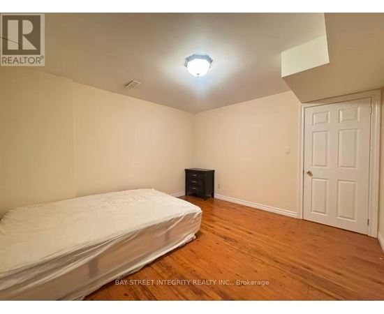 A bedroom with a bed, dresser, and a door.