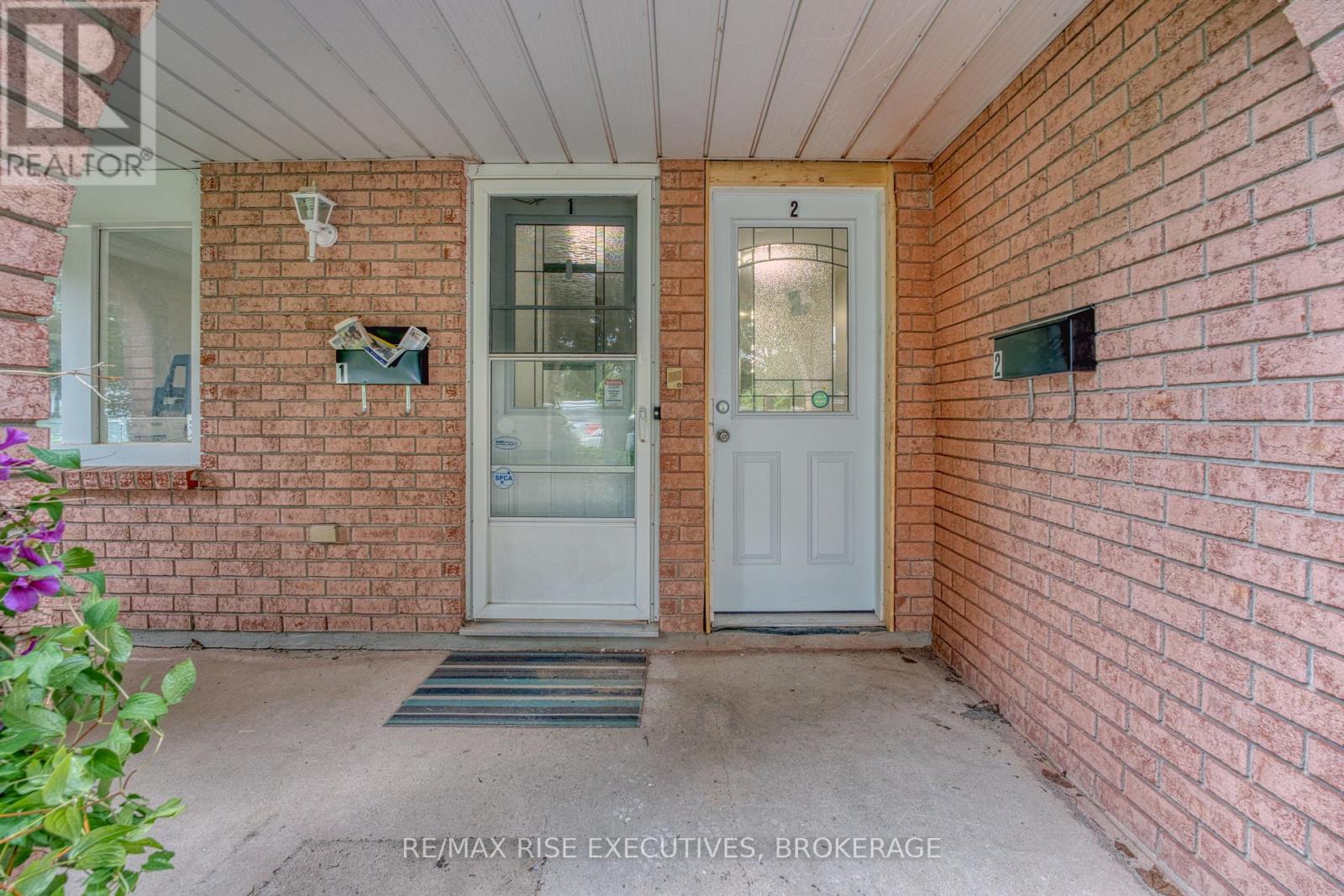 A white door with a glass window is on the front of a brick house.
