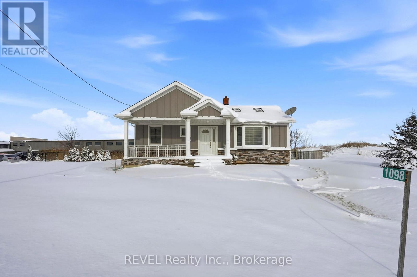 A house with a snowy front yard and a sign that says REVEL Realty Inc., Brokerage.