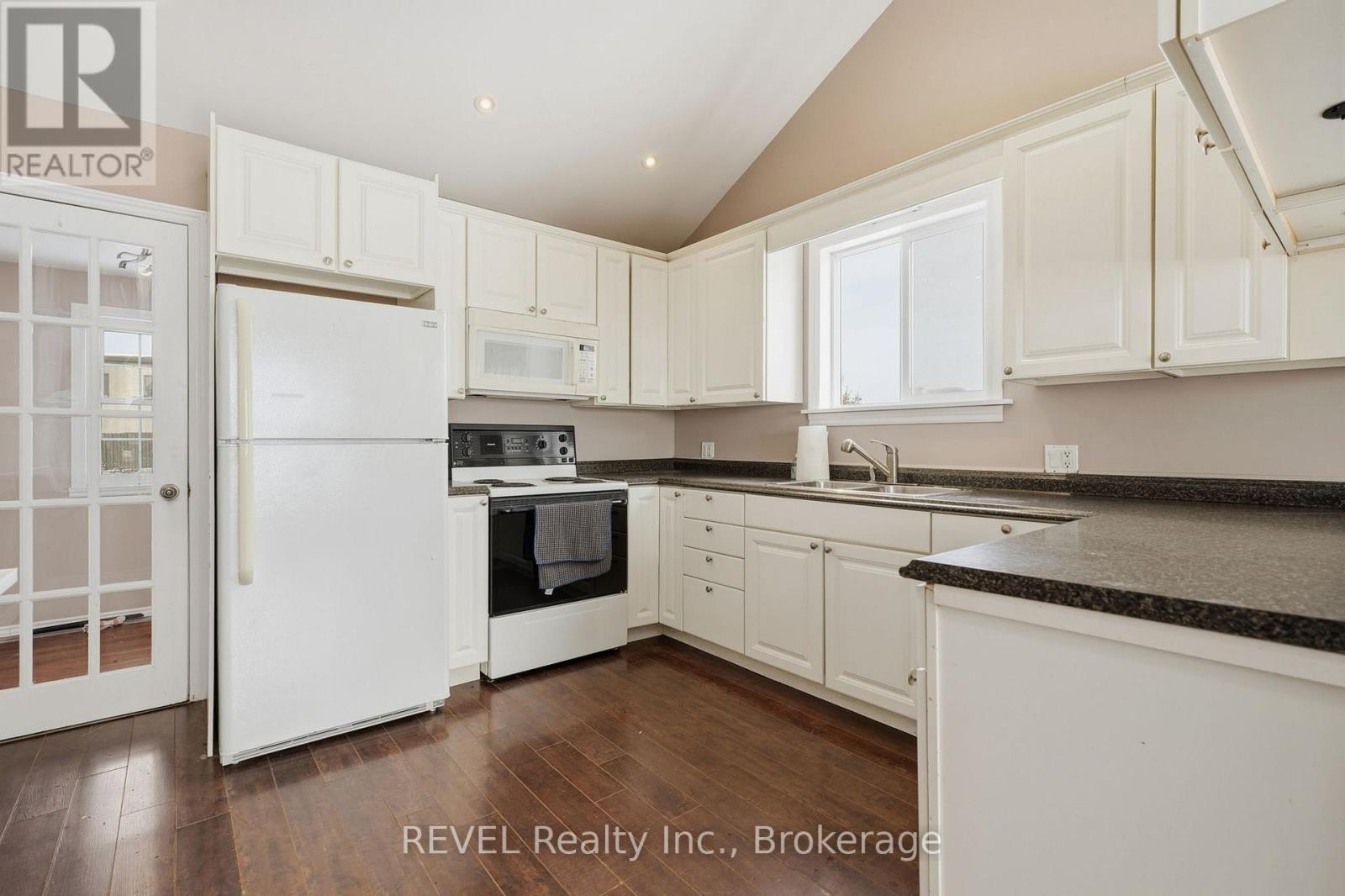 A kitchen with white cabinets and appliances is on the market with REVEL Realty Inc.