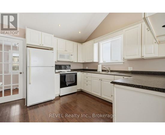 A kitchen with white cabinets and appliances is on the market with REVEL Realty Inc.