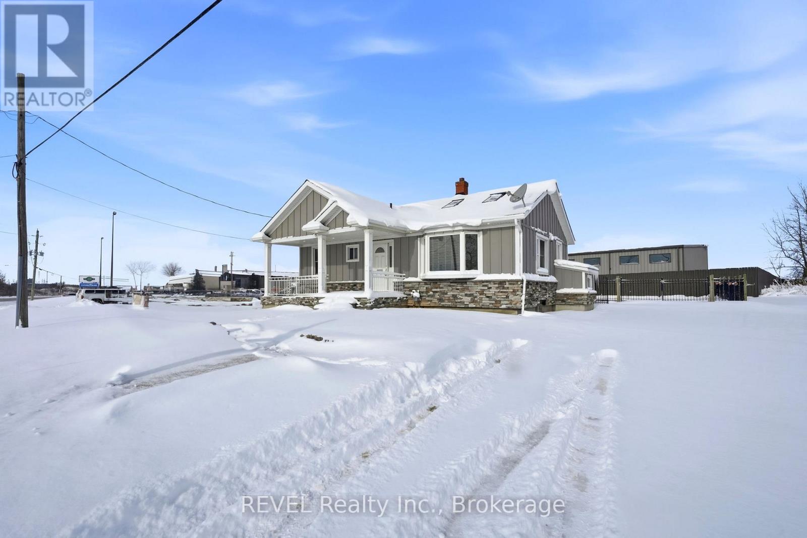 A house in the snow with a REVEL Realty Inc. sign.